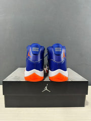 Rear view of the pair showing blue heel panels, orange branding, white midsoles, and orange heel traction.