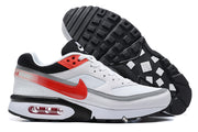 Side view of white, red, and grey Nike Air Max sneakers with the outsole visible