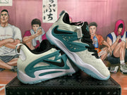 Angled view of a pair of cream and teal Nike sneakers displayed with one shoe resting on the other.