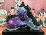 Angled view of the purple-blue galaxy-patterned sneaker pair, showing the black upper, lace closure, molded side panels, and translucent soles.