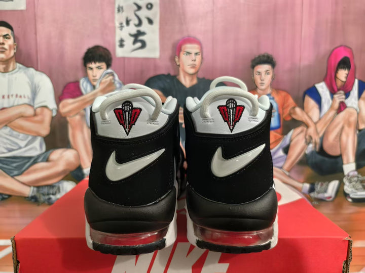 Rear view of white and black Nike basketball sneakers with red accents and visible air cushioning, displayed on a Nike box.