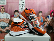 Angled view showing the graphic upper, orange collar, black Swoosh, white midsole, and black outsole of the Nike basketball sneakers.