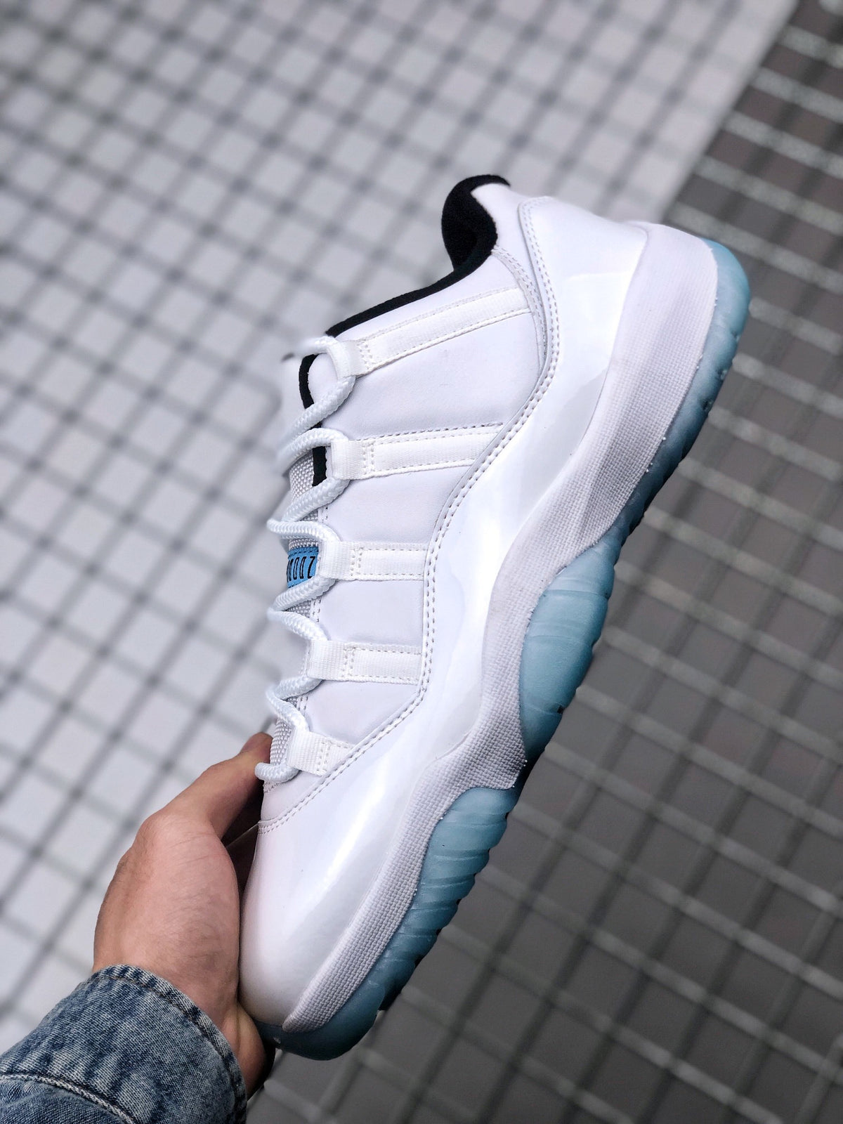 Side view of a white Jordan Air Jordan 11 Low sneaker with a translucent blue outsole and black collar detail.
