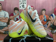 Angled view of pink and white basketball shoes with black Swoosh branding and green outsoles