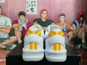 Rear view of white basketball sneakers showing yellow heel panels and textured outsole sections.