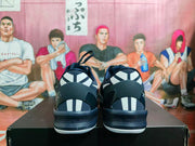 Rear view of navy blue sneakers showing white heel accents, black midsoles, and white outsole edges.