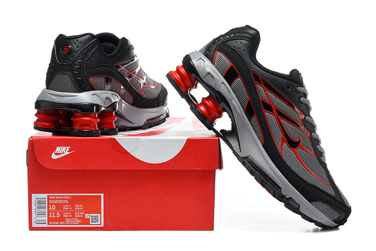 Nike Shox Ride 2 sneakers in black, grey, and red displayed with a red shoe box; the box label shows a sample size.