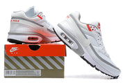White, grey, and red Nike Air Max sneakers displayed on a shoebox