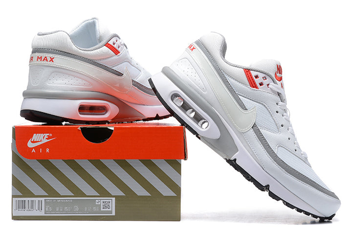 White, grey, and red Nike Air Max sneakers displayed on a shoebox