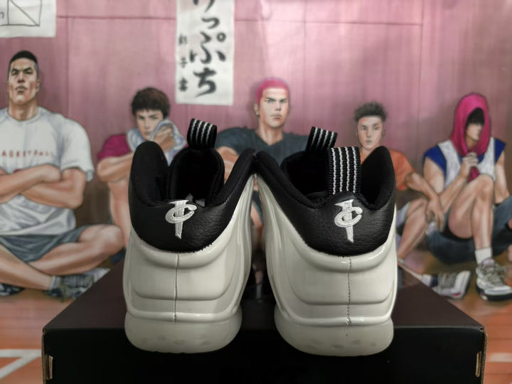 Rear view of white and black high-top sneakers showing padded black collars, striped pull tabs, and heel emblems.