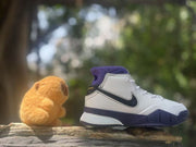 Side profile of a white high-top sneaker with black Swoosh branding, purple collar, and dark purple outsole.