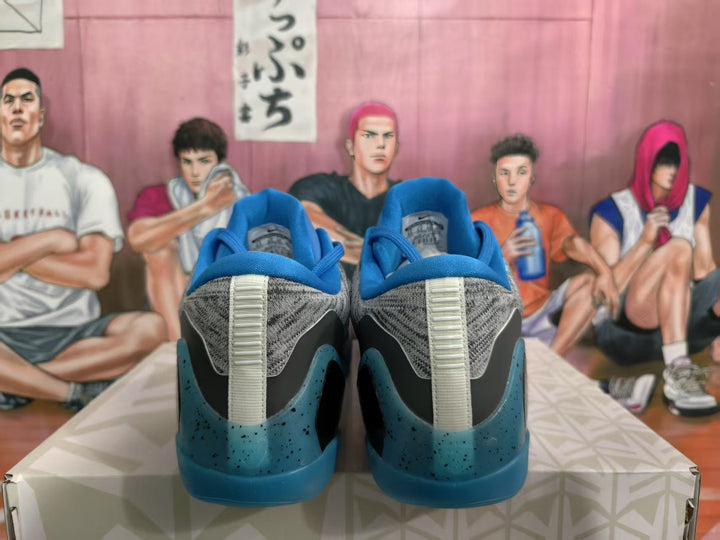 Rear view of gray and blue Nike basketball sneakers showing blue heel panels, gray uppers, and speckled blue outsoles.