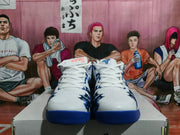 Front view of the pair showing white uppers, white laces, blue outsole edges, and dark blue toe graphics.