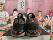 Rear view of black Nike sneakers showing perforated heel panels, red branding details, and layered soles.
