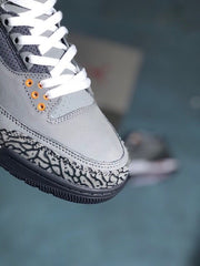 Close-up of the grey sneaker toe, white laces, orange eyelets, and elephant-print overlay