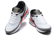 Top and front views of a pair of white, grey, and black Nike Air Max sneakers with red accents.