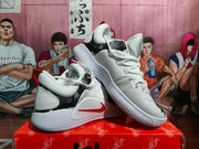 Angled view of a pair of Nike basketball sneakers with padded collars, lace fastening, gray patterned panels, and red pull tabs.