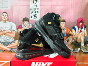 Angled view of black and gold Nike high-top sneakers showing the side design and heel cushioning