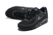 Angled view of black Nike Air Max 90 sneakers with lace-up fronts and patterned lining.