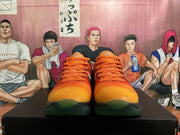 Front view of orange-to-yellow textured basketball shoes with orange laces and dark green toe accents