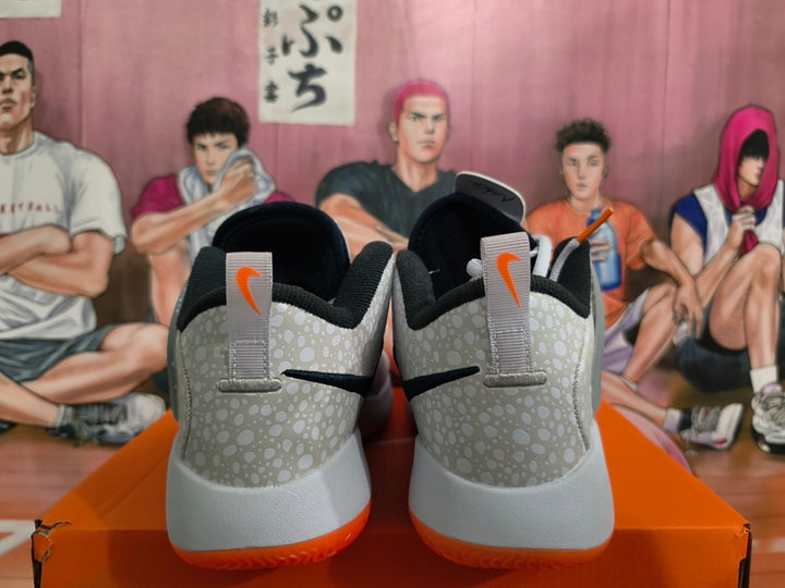 Rear view of gray and white Nike basketball shoes with dotted heel panels and orange outsole edges.