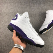 Hand-held view of the white and purple Air Jordan 13 sneaker