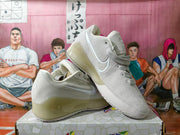 Angled view of off-white Nike basketball shoes highlighting the Swoosh and translucent-looking sole.