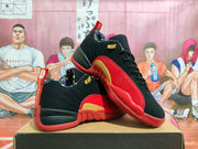 Angled product view of black, red, and gold basketball sneakers arranged on a box.