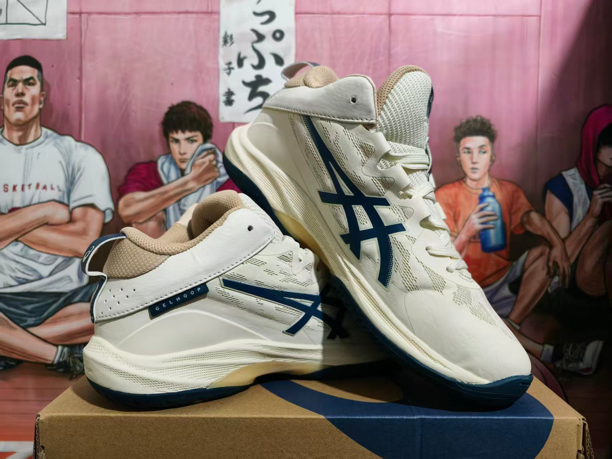 Pair of cream ASICS basketball sneakers with navy logos and outsole accents, shown at an angle.