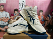 Pair of cream ASICS basketball sneakers with navy logos and outsole accents, shown at an angle.