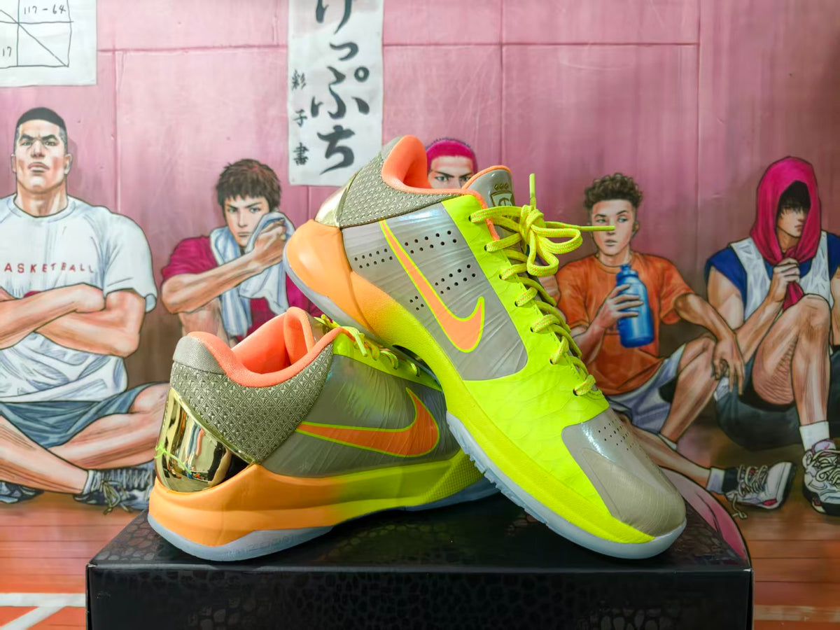 Pair of neon green, olive, orange, and gray Nike basketball sneakers displayed on a black box.