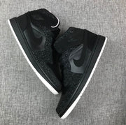 Top-down view of two black sneakers showing the laces, collars and side panels.