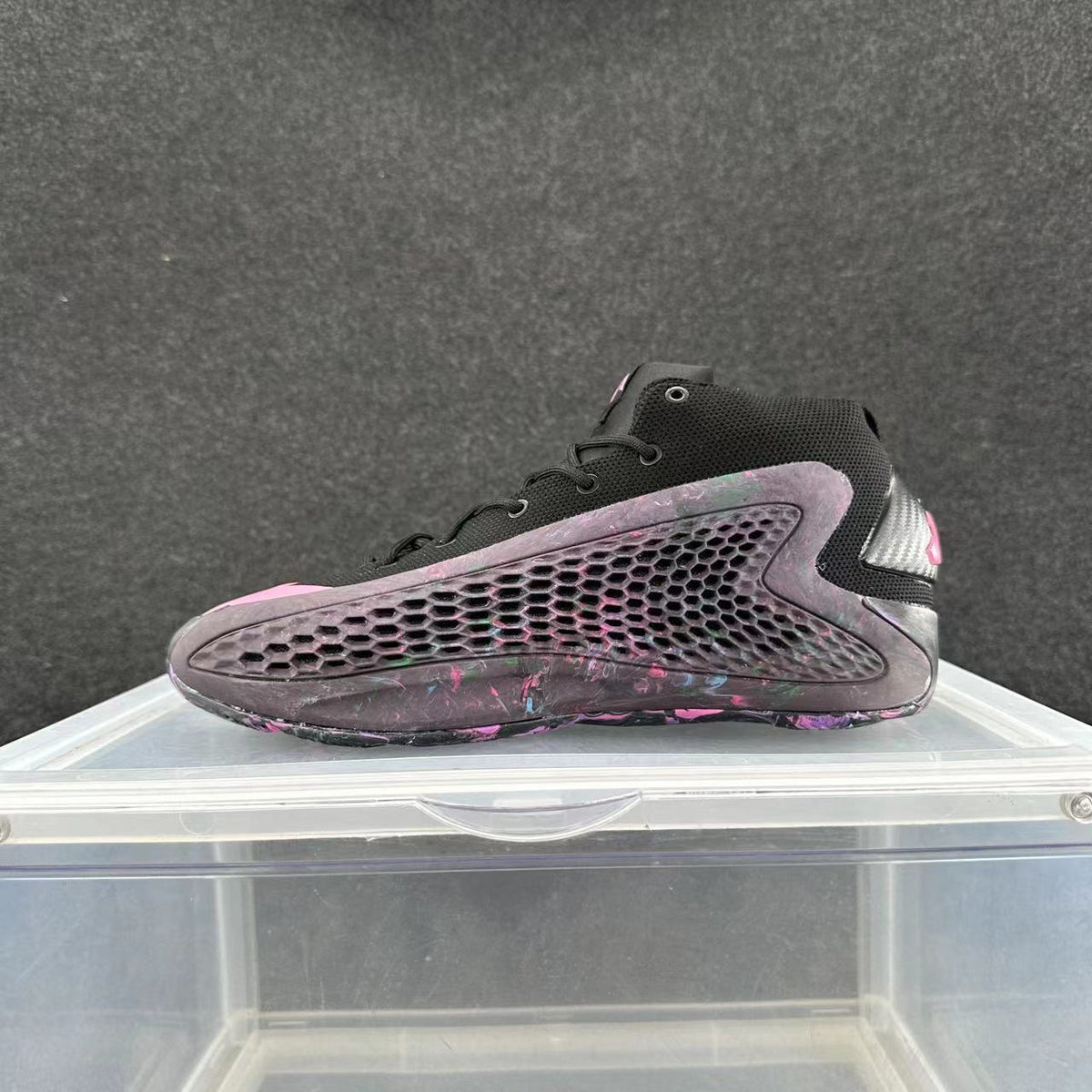 Side view of a black high-top sneaker with a honeycomb-pattern panel and purple and pink accents.