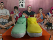 Front view of mismatched mint green and yellow sneakers with red tongue labels, colored laces, and white soles.