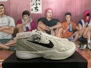 Side view of a white Nike basketball shoe showing a black Swoosh, star-patterned side panel, circular graphic, and Zoom-branded midsole.