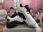Angled view of the black-and-white basketball sneakers highlighting the gold eyelets, decorative trim, patterned laces, and side branding.