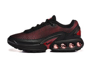 Side view of black sneakers with red patterned detailing and circular cushioning elements