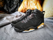 Pair of black and gold high-top sneakers displayed together on gray fabric.