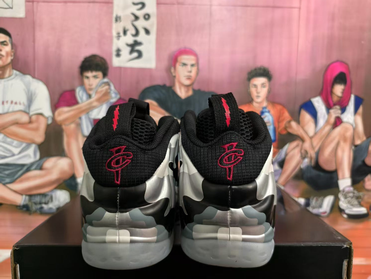 Rear view of black camouflage-style sneakers with red heel embroidery and translucent gray outsoles.