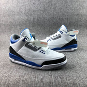 Three-quarter product view of the pair on a gray textile background, showing the white, blue, and black color blocking.