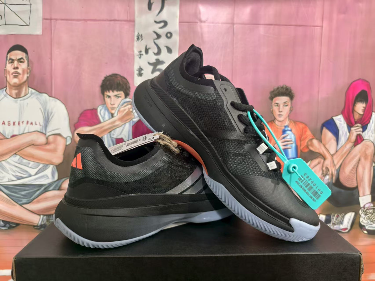 Pair of black Adidas shoes with white side stripes and light-colored outsoles, shown from the side.