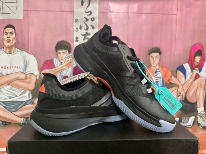 Pair of black Adidas shoes with white side stripes and light-colored outsoles, shown from the side.