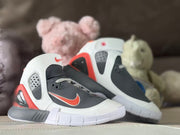 Angled product view showing the dark gray toe area, white overlays, red accents, and white outsole.