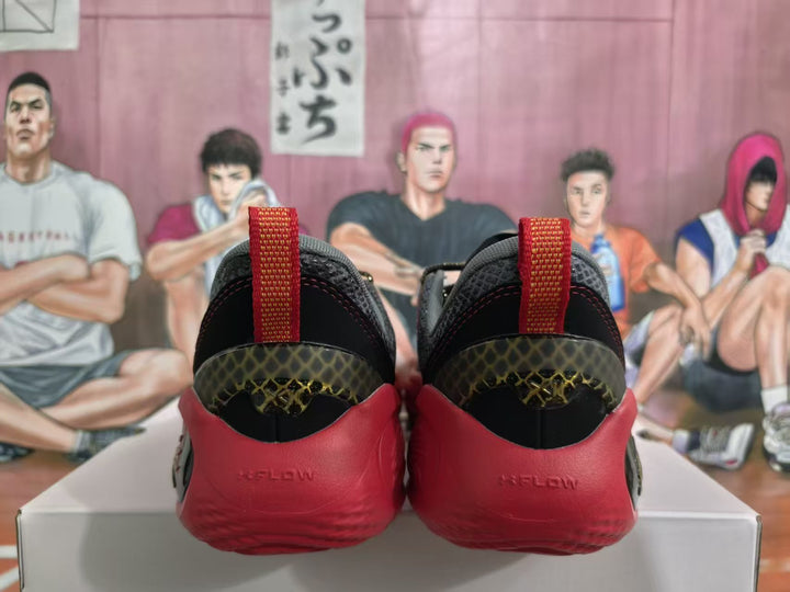 Rear view of black and red basketball sneakers showing red heel sections, red pull tabs, and gold-patterned heel panels.