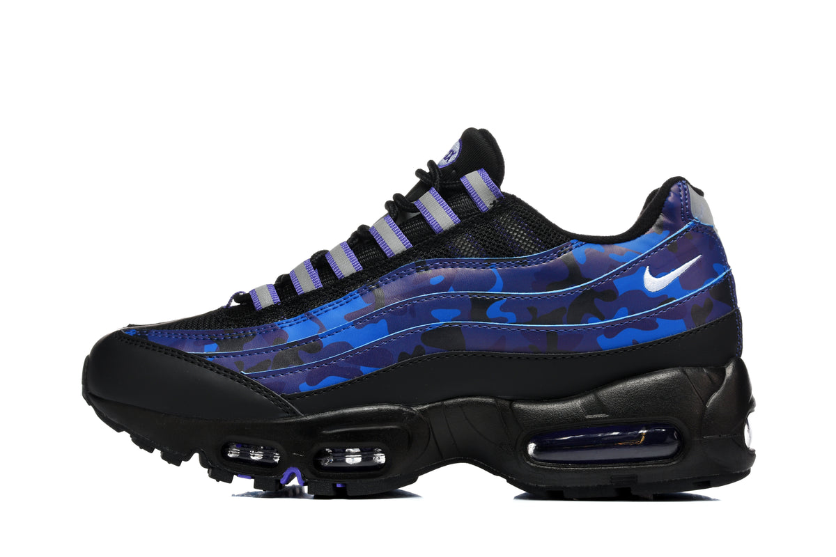 Side view of a black Nike sneaker with blue and purple camouflage-patterned panels, purple lace accents, a white Swoosh, and a black sole.
