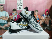 Pair of white, black and gold basketball sneakers displayed on a box, showing the patterned upper, gold swoosh and black outsole.
