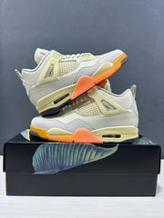 Pair of light-colored Jordan Air Jordan 4 sneakers arranged on a black illustrated shoe box, showing orange outsole sections and pale yellow details.