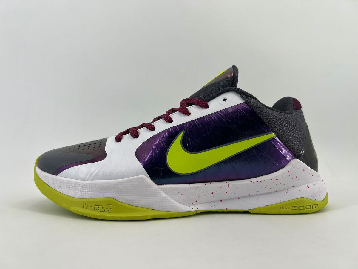 Side view of a Nike low-top basketball shoe in white, purple, charcoal, and lime with dark red laces and a speckled midsole