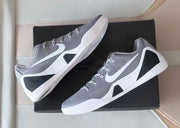 Pair of grey and white low-top shoes shown from side and angled views on a box.