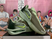 Angled view showing the olive green Nike shoes, ribbed forefoot panels, and lime Swoosh